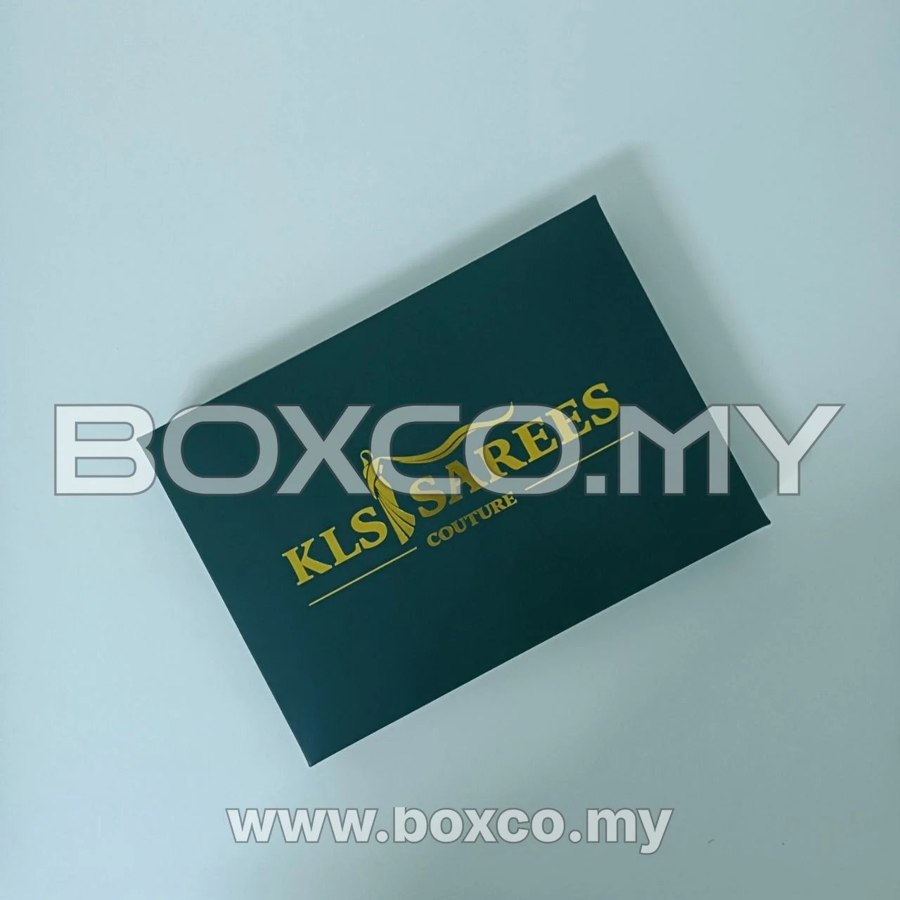 Top view of dark green saree box lid with centred gold artwork
